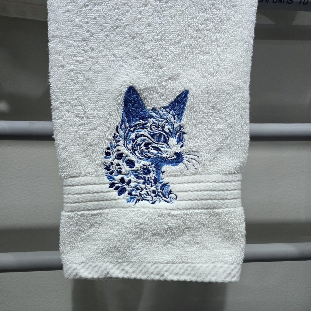Cat silhouette embroidered on cotton hand towel, abstract blue design